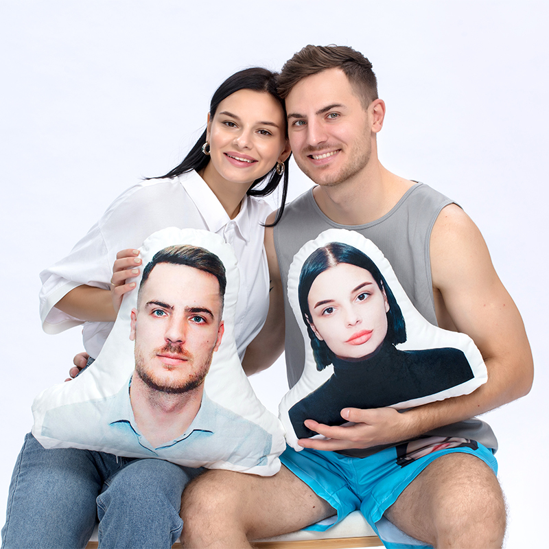 Couple holding custom face-shaped photo pillows of each other